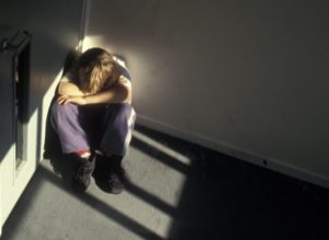 Young boy sitting in dark corner of stairs. Victim of child abuse