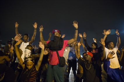 Demonstrators confront police with their arms raised during on-going demonstrations to protest against the shooting of Mic...