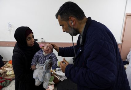 A Palestinian child is examined by a doctor at a health center in Rafah