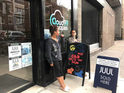 Natalia Pena and Rizza Colon vape outside the shop they work at, Cloud99 Vapes, in Manhattan borough, New York