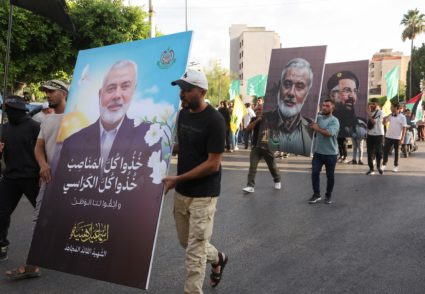 Demonstrators hold pictures of Haniyeh and Shukr during in a protest in Sidon
