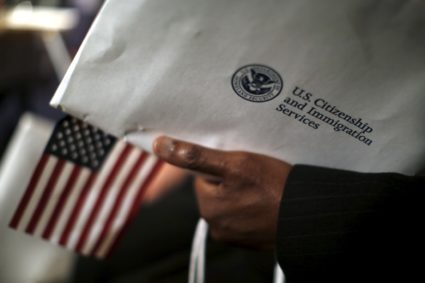 A man holds an envelope from the U.S. Citizenship and Immigrations Service during a naturalization ceremony at the Nationa...