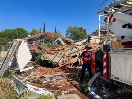 A firefighter works at the site of a house that was damaged after rockets were fired from Lebanon, in Katzrin in the Israe...