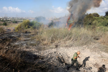 An Israeli policeman walks next to a crater inside an impact spot following a missile attack from Yemen