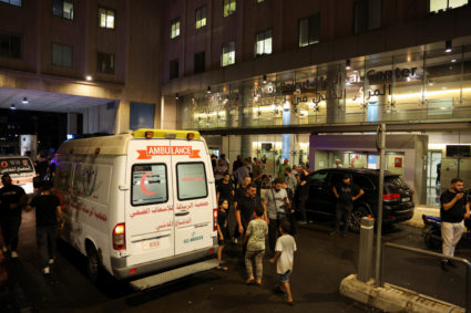 People walk near an ambulance outside American University of Beirut Medical Center, including Hezbollah fighters and medic...