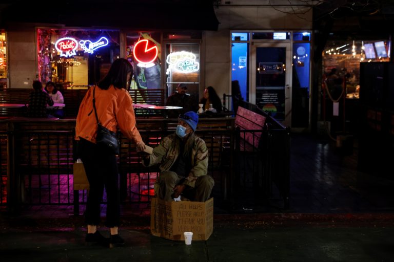 Woman hands a meal to a man stating to be a homeless veteran along Downtown 8th Street in Boise, Idaho