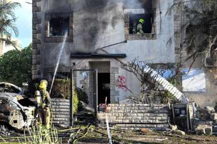Firefighters work to put out a fire on a house that was damaged by rocket fire from Lebanon on Israel, amid cross-border h...