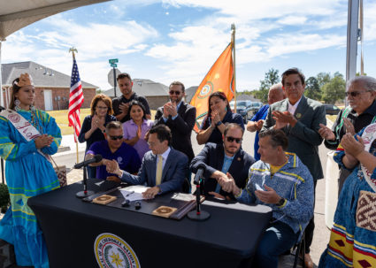 Representatives of the Cherokee Nation, including Principal Chief Chuck Hoskin Jr., shake hands after signing an extension to affordable housing legislation for Cherokee citizens. Photo provided by Cherokee Nation
