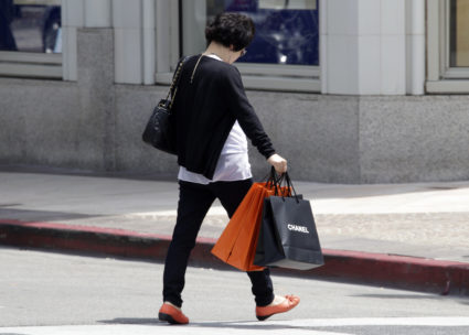 A woman carrying a Chanel shopping bag walks on Rodeo Drive in Beverly Hills