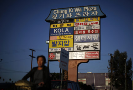 Woman cycles past a mall sign in Korean in the Koreatown area of Los Angeles