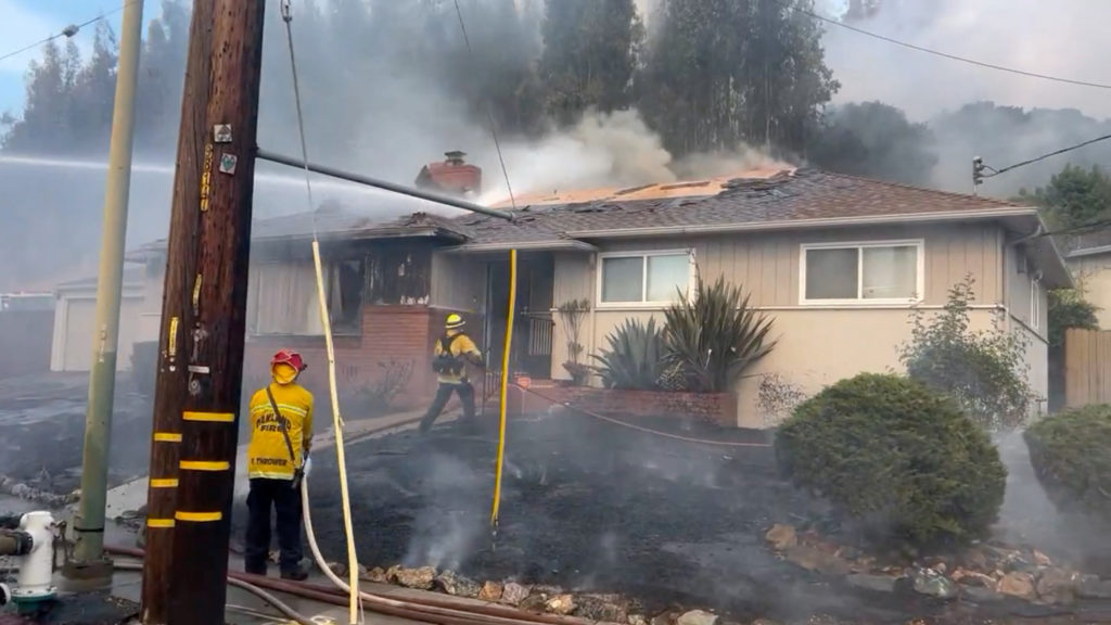Firefighters work to stop a fire that damaged homes, in Oakland