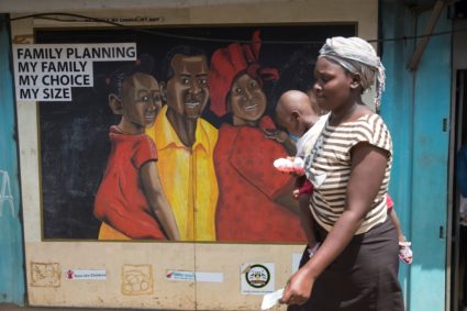 A woman walks past a murel outside a Family Health Options clinic in the Kibera slums in Nairobi, Kenya