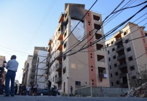 People stand at the site hit by an Israeli strike in the northern Lebanese city of Tripoli