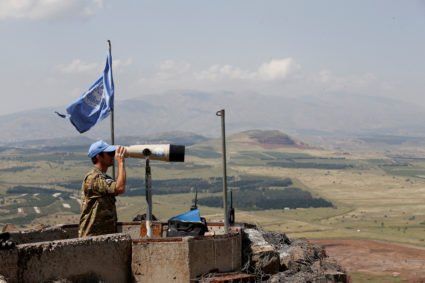 FILE PHOTO: A United Nations Truce Supervision Organisation military observer uses binoculars near the border with Syria i...
