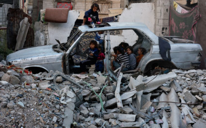 Palestinian children gather at a destroyed vehicle in Khan Younis
