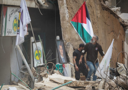 People stand on the rubble after an Israeli strike in Ras Al-Nabaa, in Beirut