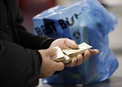 A customer counts his cash at the register while purchasing an item at a Best Buy store in Flushing