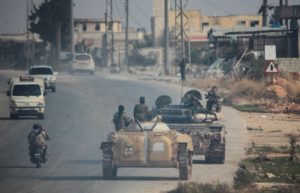 Rebels led by the Islamist militant group Hayat Tahrir al-Sham drive along a street in al-Rashideen, Aleppo province