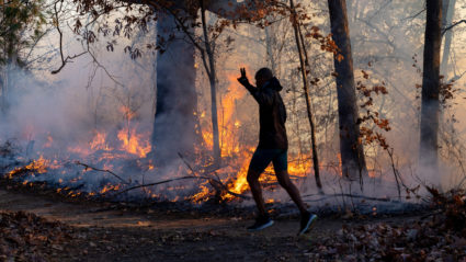 A morning jogger gestures as he runs past a fire lit by members of the New Jersey Forest Fire Service as it burns alongsid...