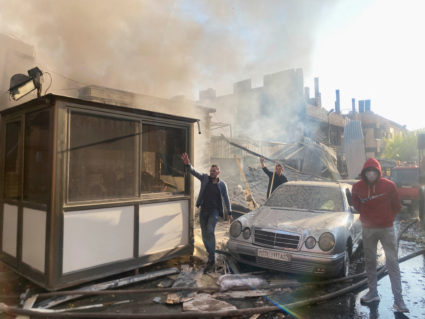 Smoke rises as people gesture at a damaged site after what Syrian state news agency said was an Israeli strike in Damascus...