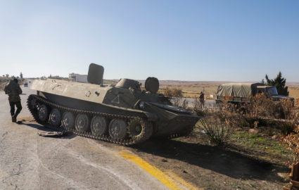 A rebel fighter stands near a military vehicle in Maarat al-Numan in Idlib province