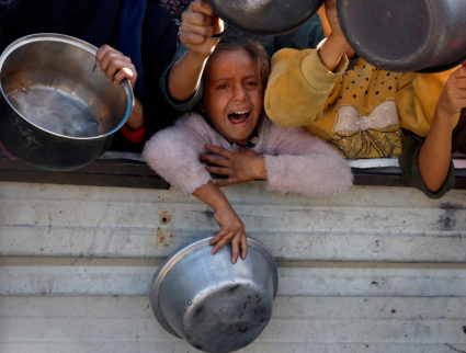 Palestinians gather to receive food cooked by a charity kitchen, amid a hunger crisis, in Khan Younis