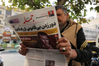 FILE PHOTO: An Iranian man reads a newspaper with a picture of Syrian President Bashar al-Assad in Tehran