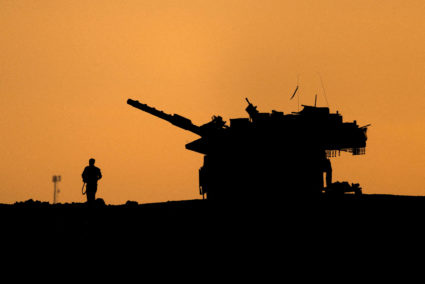 FILE PHOTO: The silhouettes of a military vehicle and a soldier are seen near the Gaza border