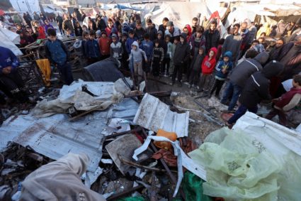 Palestinians inspect the damage at a tent camp sheltering displaced people, following an Israeli strike, in Deir Al-Balah
