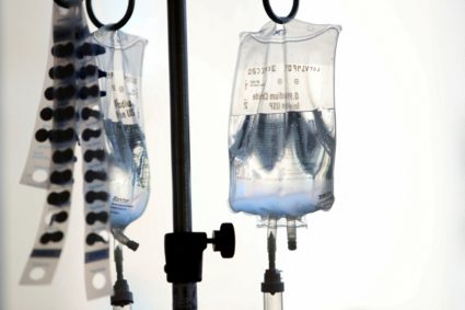 Intravenous bags hang above young cancer patients at Rady's Children Hospital as they participate in decorating golden cap...