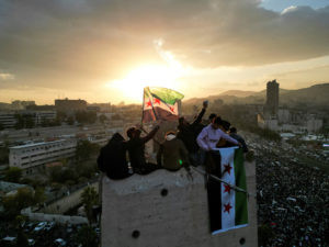 A drone view shows people waving flags adopted by the new Syrian rulers during celebrations in Umayyad Square, in Damascus