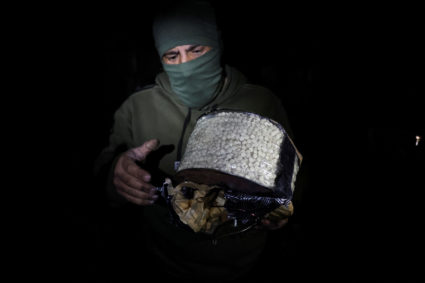 Fighter, loyal to Syria's new ruling administration, holds a box containing according to them, captagon pills, on the outs...