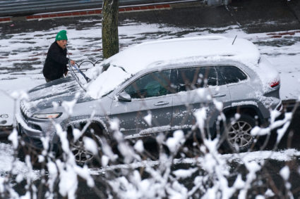 A person cleans snow from their car during the city's first snowfall of the season, on the first day of winter in the Quee...