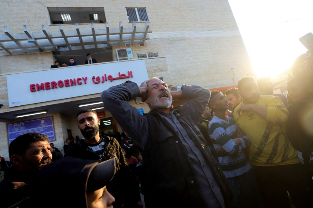 A Palestinian man reacts as casualties from an Israeli strike are brought into a hospital, in Deir Al-Balah