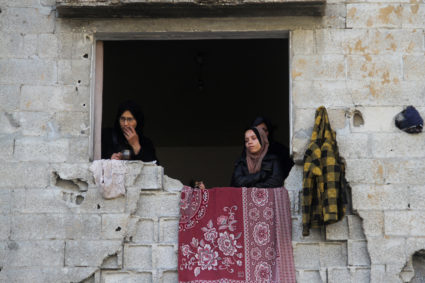 Palestinian women stand in a window of a damaged building, amid ceasefire negotiations with Israel, in Gaza City