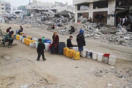 Palestinian children wait to collect water, ahead of a ceasefire set to take effect on Sunday, in Gaza City