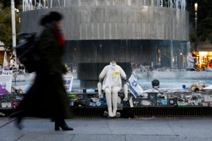 Woman walks near pictures and memorabilia related to fallen soldiers, hostages and people killed during the October 7, 202...
