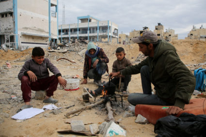Palestinians sit near the rubble of buildings destroyed during the Israeli offensive, in Rafah
