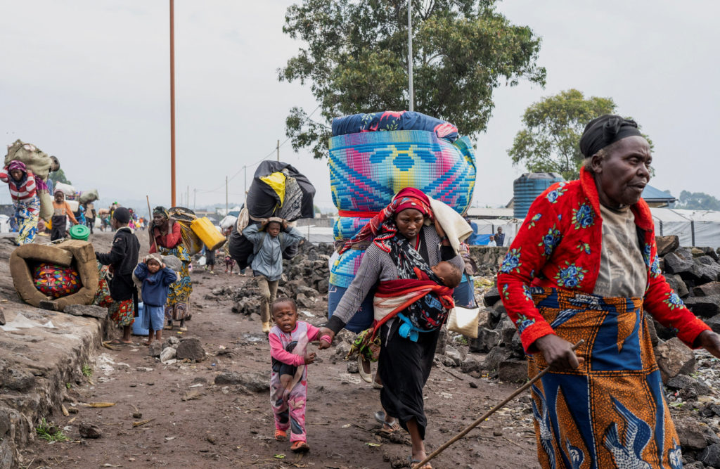 Internally displaced civilians from the camps in Munigi and Kibati, carry their belongings as they flee to Goma