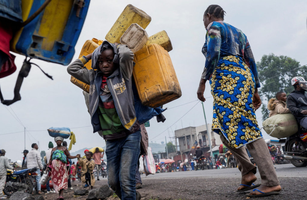 Internally displaced civilians from the camps in Munigi and Kibati, carry their belongings as they flee to Goma