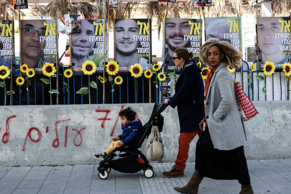 People walk past posters of hostages kidnapped during the deadly October 7, 2023 attack by Hamas, in Tel Aviv