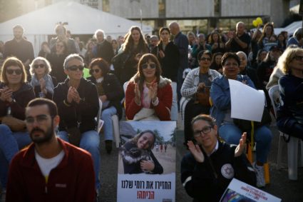 People watch broadcasts of the expected release of three female hostages, in Tel Aviv