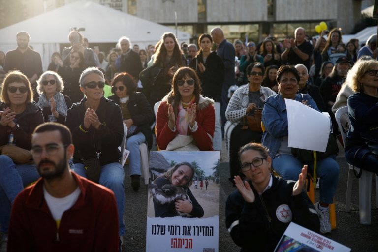 People watch broadcasts of the expected release of three female hostages, in Tel Aviv