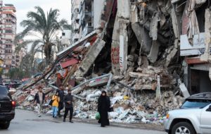 People walk near a damaged site in Beirut's southern suburbs