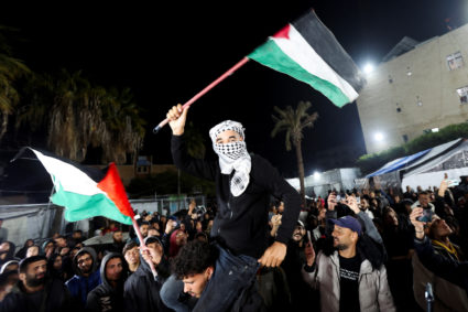A man waves Palestinian flags as Palestinians react to news on a ceasefire deal with Israel, in Deir Al-Balah in the centr...