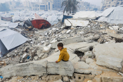 A Palestinian child sits amid the rubble of buildings destroyed in previous Israeli strikes, ahead of a ceasefire set to t...