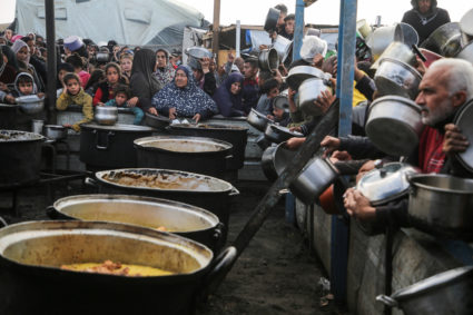 Palestinians gather to receive food cooked by a charity kitchen, in Khan Younis