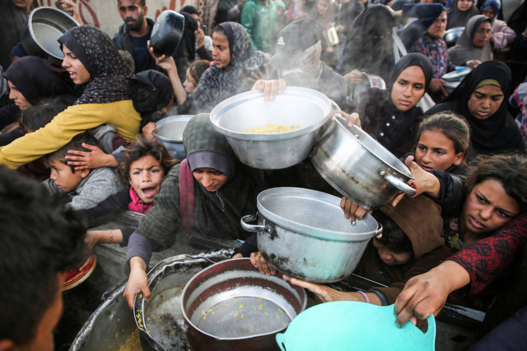 Palestinians gather to receive food cooked by a charity kitchen, in Khan Younis