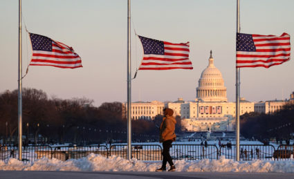 U.S. flags fly at half staff with the U.S. Capitol building in the distance in Washington