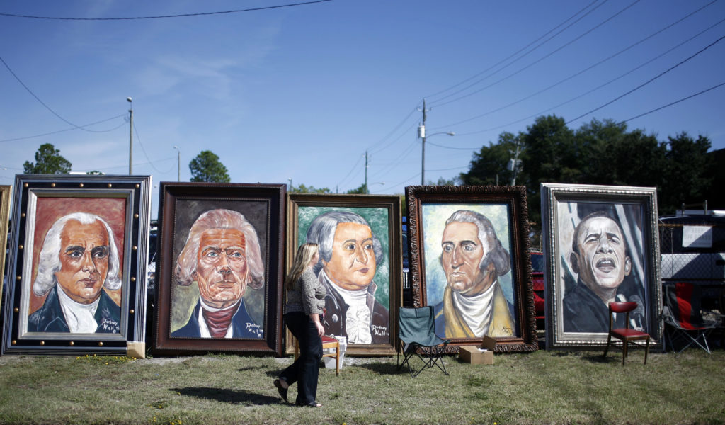 A woman walks next to painted pictures of former U.S. presidents and Democratic U.S. presidential nominee Sen. Obama outsi...